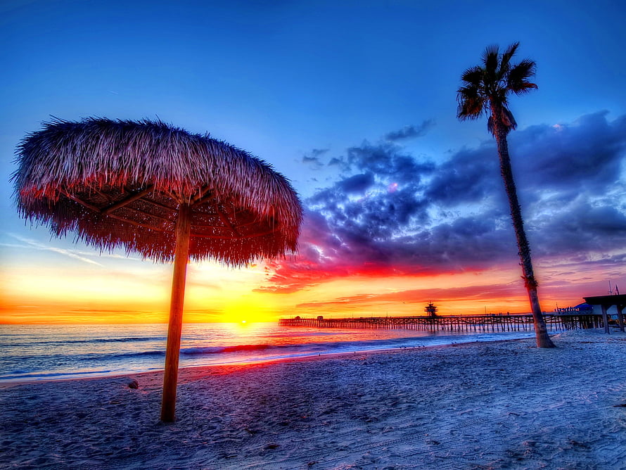 Tropical Beach Sunset With Thatched Umbrella, Palm Tree, And Pier Silhouette HD wallpaper