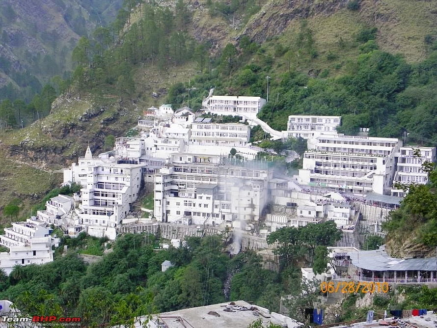 White buildings on a lush green hillside with smoke rising HD wallpaper
