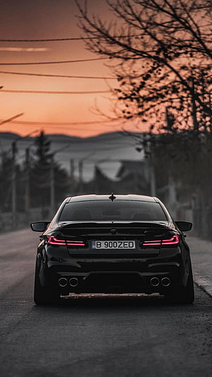 Rear View of a Black BMW M5 F90 Sedan on a Quiet Road at Sunset HD phone wallpaper