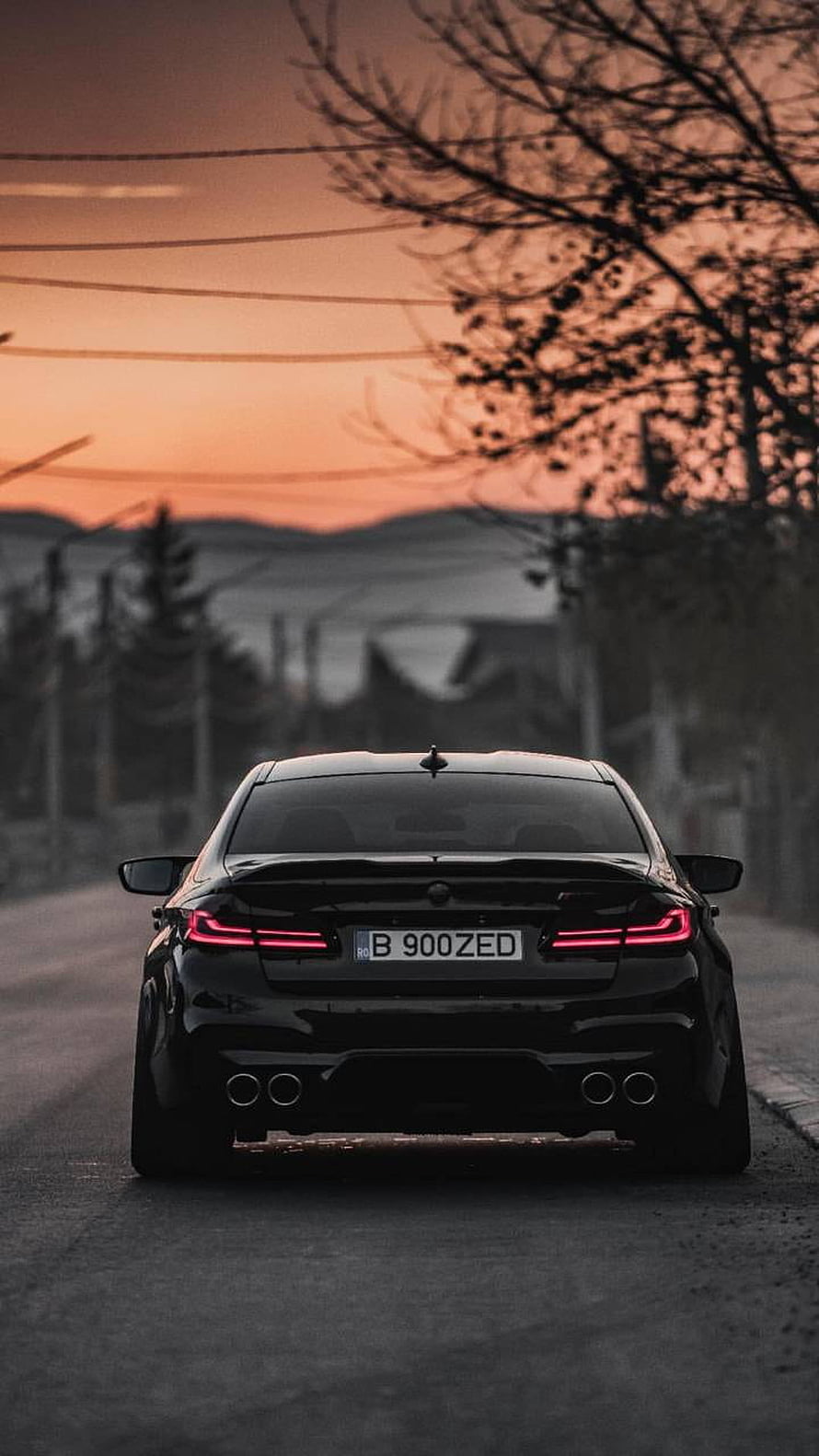 Rear View of a Black BMW M5 F90 Sedan on a Quiet Road at Sunset HD phone wallpaper