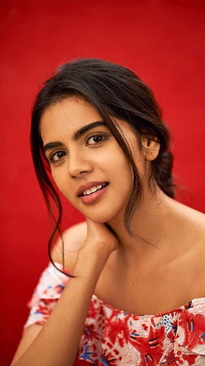 Kalyani Priyadarshan Portrait in Floral Top Against Red Background HD phone wallpaper