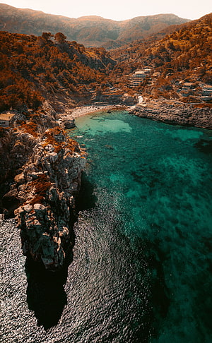 Aerial View of Turquoise Bay Surrounded by Rocky Cliffs and Pine Forests HD phone wallpaper