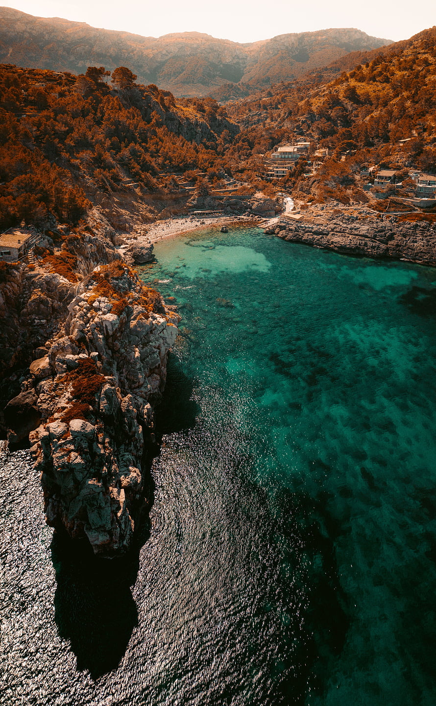 Aerial View of Turquoise Bay Surrounded by Rocky Cliffs and Pine Forests HD phone wallpaper