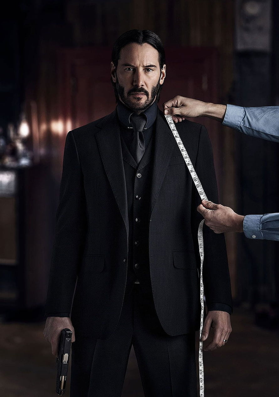 Keanu Reeves as John Wick in a black suit holding a gun during a tailoring scene HD phone wallpaper