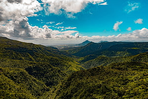 Lush Green Mountain Ranges Under a Bright Blue Sky with Scattered Clouds HD wallpaper