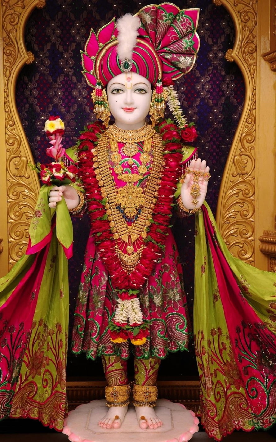Lord Krishna Idol in Pink and Green Attire with Golden Jewelry and Flower Garland HD phone wallpaper