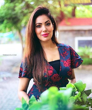 Munmun Dutta in a floral dress with long hair and bright pink lipstick in a garden setting HD phone wallpaper