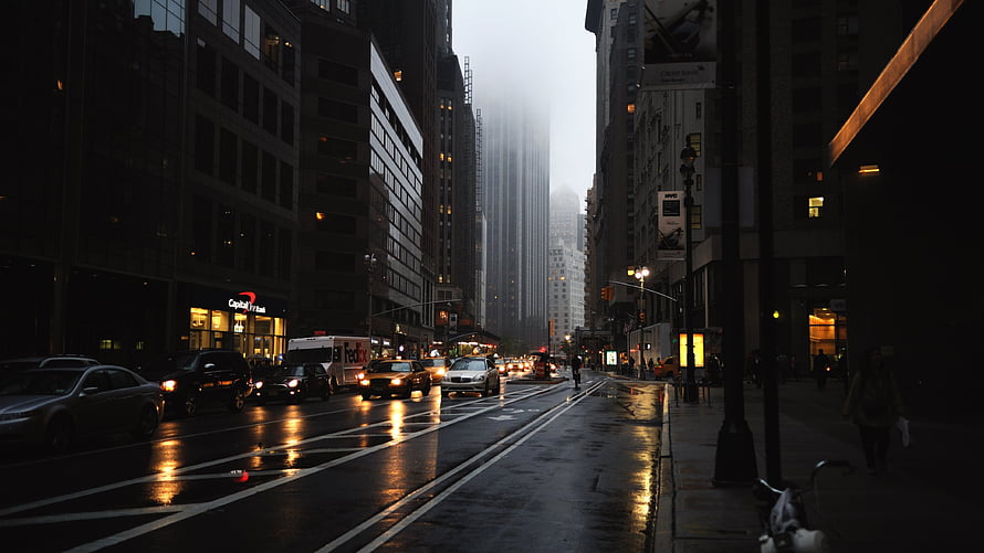 Foggy City Street with Wet Pavement and Glowing Car Headlights HD wallpaper