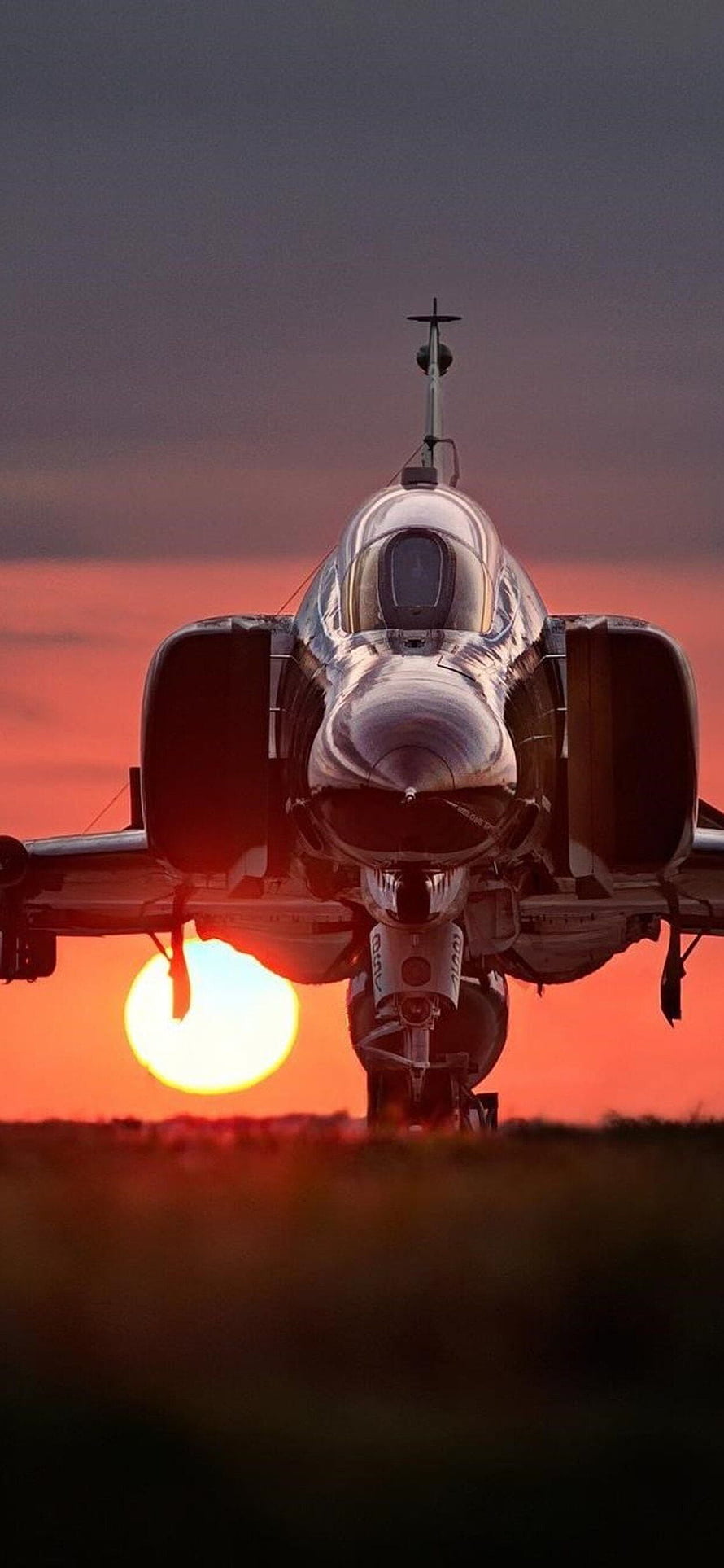 Front View of a Military Jet Fighter Silhouetted Against a Dramatic Sunset Sky HD phone wallpaper