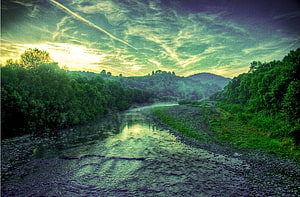 Serene River Landscape with Lush Green Forests and Dramatic Sky HD wallpaper