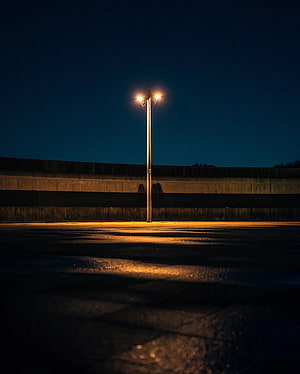 Lone Street Lamp Illuminating an Empty Parking Lot Under a Starry Night Sky HD phone wallpaper