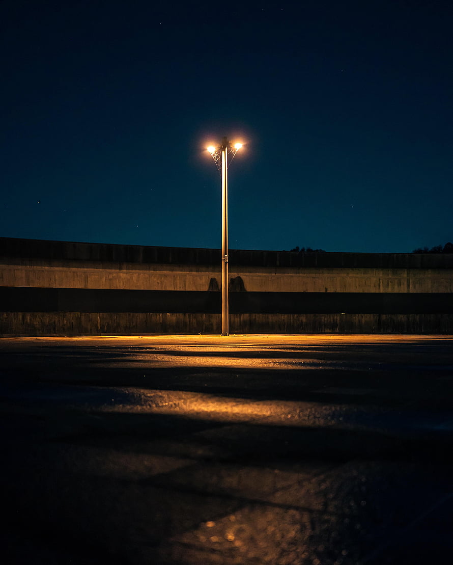 Lone Street Lamp Illuminating an Empty Parking Lot Under a Starry Night Sky HD phone wallpaper