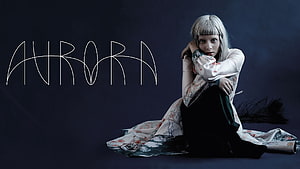 Aurora Aksnes in a floral robe seated against a dark studio backdrop HD wallpaper