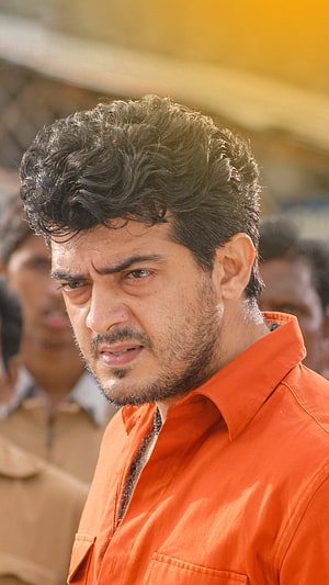 Vijay Sethupathi in an orange shirt with an intense expression and curly hair HD phone wallpaper