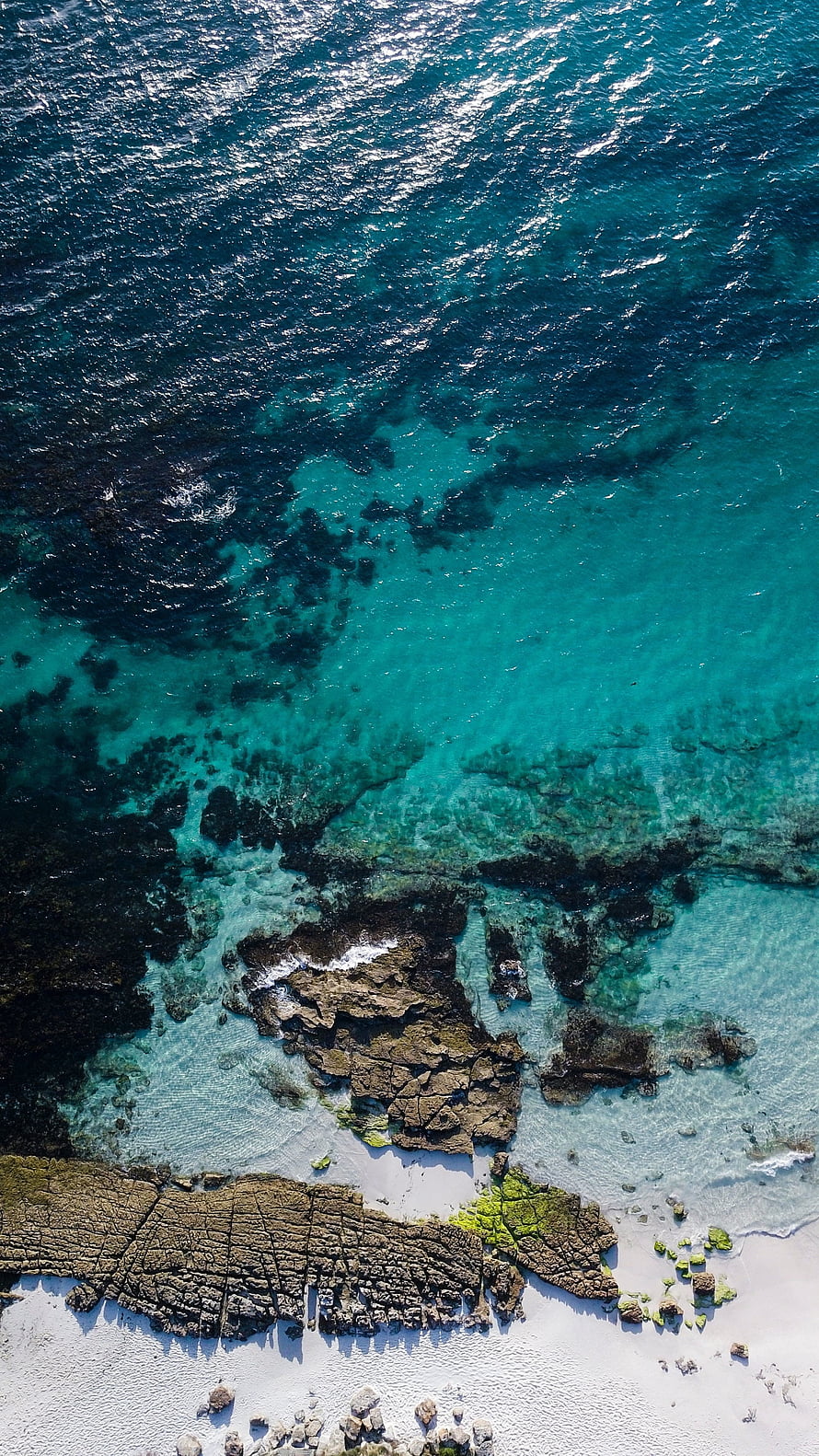 Aerial View of Turquoise Ocean Water Over Rocky Coastline and White Sand Beach HD phone wallpaper