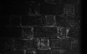 Dark Grunge Brick Wall Texture with Deep Shadows and Weathered Stone Surface HD wallpaper
