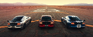 Three Ford Mustang Shelby GT500 muscle cars lined up on a desert runway at sunset HD wallpaper