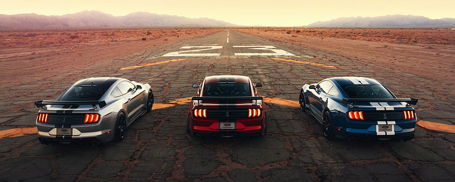 Three Ford Mustang Shelby GT500 muscle cars lined up on a desert runway at sunset HD wallpaper