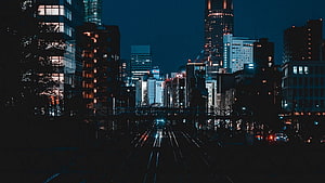 Nighttime Cityscape with Train Tracks and Illuminated Skyscrapers HD wallpaper