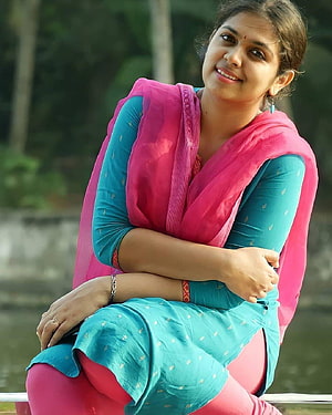 Anjali Nair in a teal kurta and pink dupatta, seated outdoors with a warm smile HD phone wallpaper