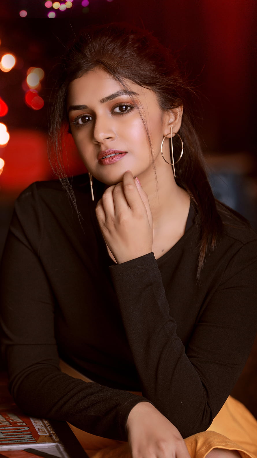 Sanjana Anand Portrait in Black Top with Gold Hoop Earrings Against Warm Bokeh Lights HD phone wallpaper