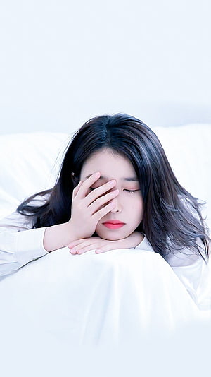 IU Resting on White Pillow with Hand Over Eyes in Soft Minimalist Portrait HD phone wallpaper