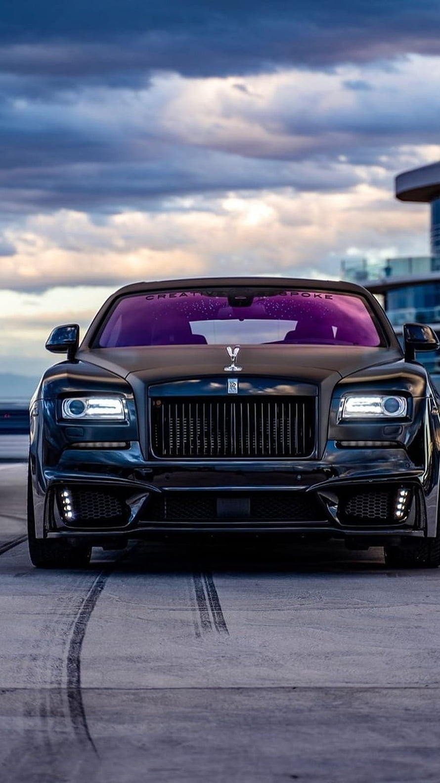 Rolls Royce Ghost Front View with Dramatic Skyline and Purple Tinted Windshield HD phone wallpaper