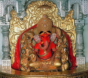 Red Ganesha Statue with Golden Crown and Ornate Temple Shrine Background HD wallpaper