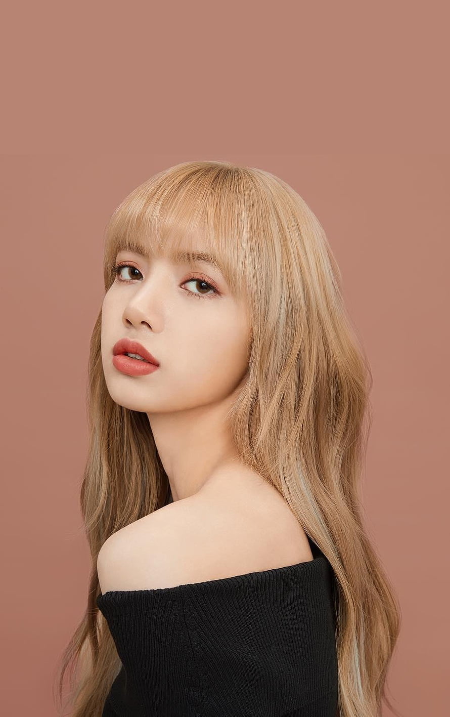 Lisa from BLACKPINK in a black off-shoulder top with long blonde hair and bangs against a warm brown studio background HD phone wallpaper