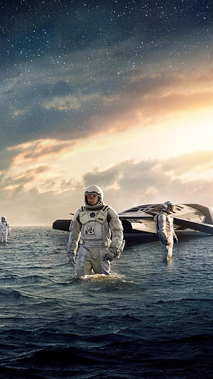 Interstellar astronauts wading through water with spacecraft under a starry sky HD phone wallpaper