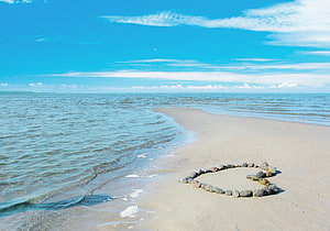 Heart Shape Made of Stones on Sandy Beach by Ocean Waves HD wallpaper
