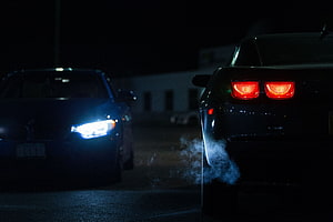 Two sports cars facing off at night with glowing headlights and tire smoke HD wallpaper