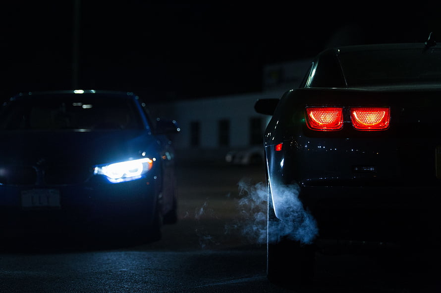 Two sports cars facing off at night with glowing headlights and tire smoke HD wallpaper