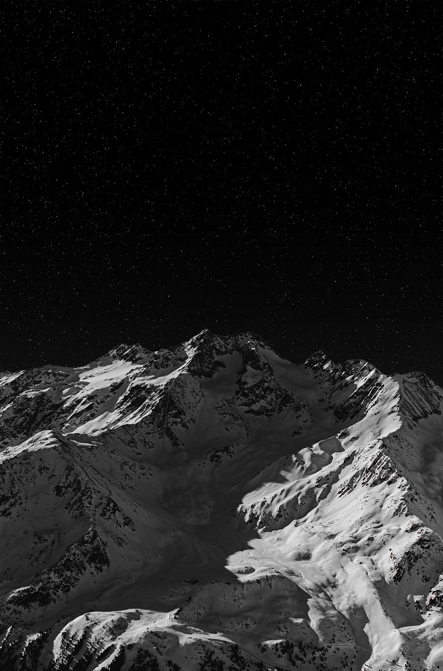 Snow-Covered Mountain Peaks Under a Starry Night Sky in Black and White HD phone wallpaper