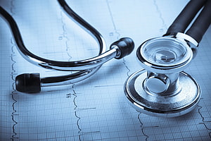 Stethoscope Resting on ECG Heartbeat Chart with Medical Grid Background HD wallpaper