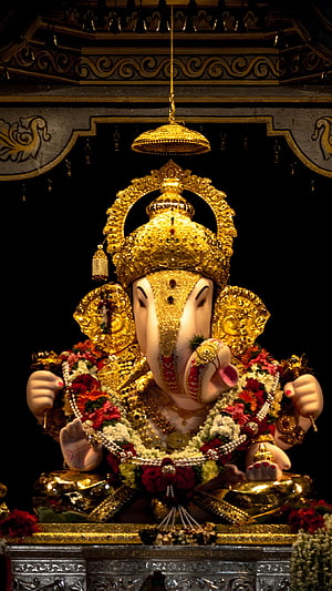 Ornate Golden Ganesha Murti Adorned with Fresh Flower Garlands in a Temple Setting HD phone wallpaper