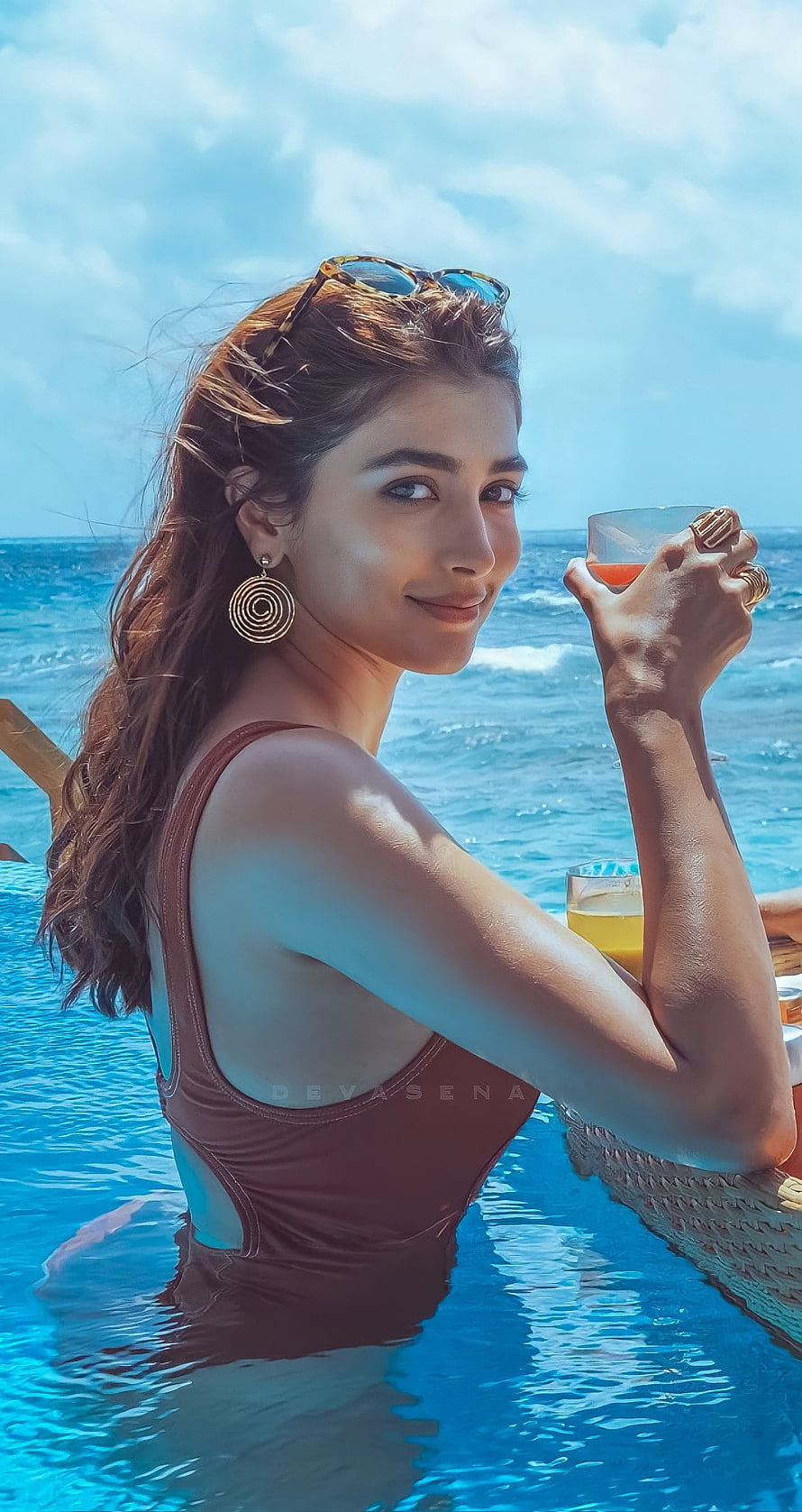 Pooja Hegde in a brown swimsuit relaxing in an infinity pool with ocean view HD phone wallpaper