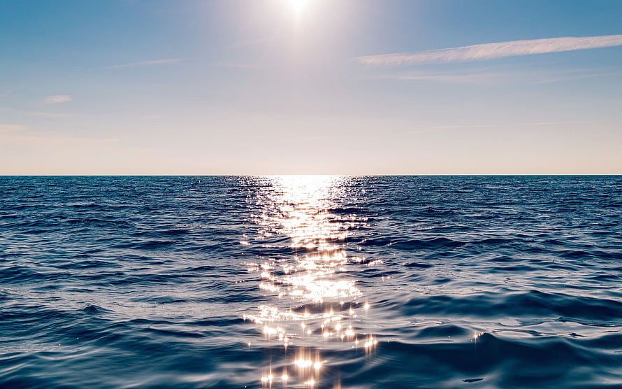 Sunlight Glinting on Deep Blue Ocean Waves Under a Clear Sky HD wallpaper