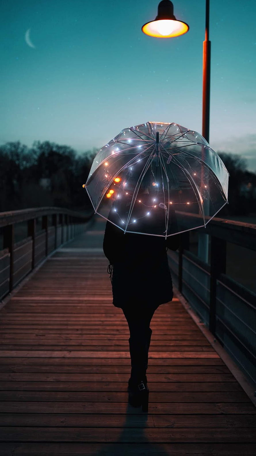 Person Walking on Wooden Bridge with Glowing Fairy Light Umbrella at Night HD phone wallpaper
