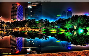 Vibrant Night Cityscape with Colorful Skyscrapers Reflected in a Park Lake HD wallpaper