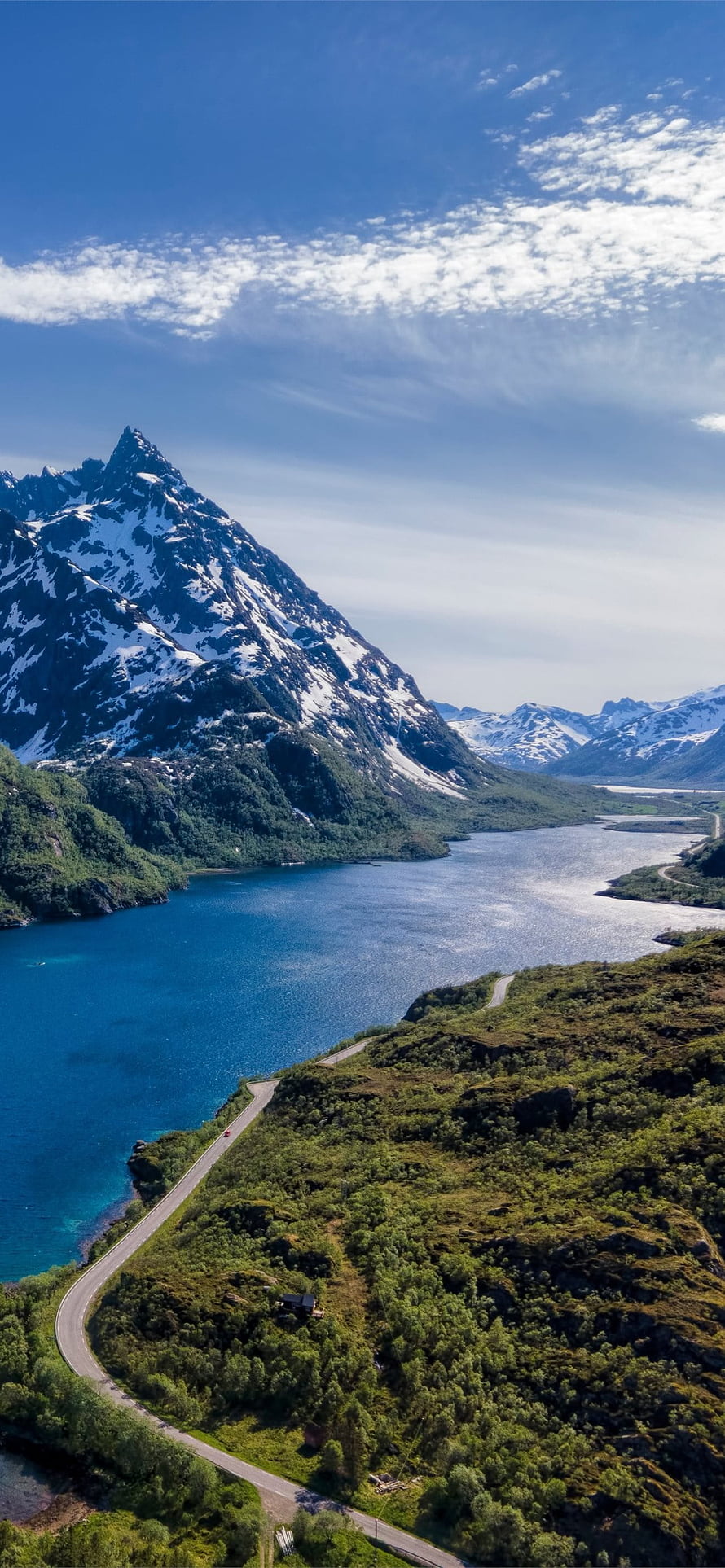 Aerial View of Snow-Capped Mountain Peak Overlooking a Deep Blue Alpine Lake and Winding Road HD phone wallpaper