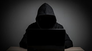 Anonymous Hacker in Black Hoodie Using Laptop in Dark Room HD wallpaper