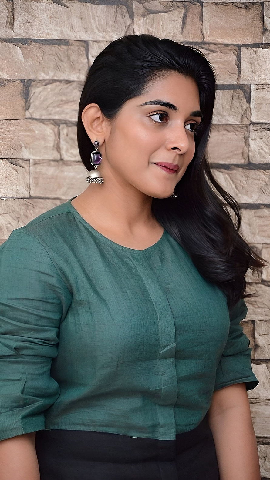 Nivetha Thomas in a Green Linen Top with Silver Earrings Against a Stone Wall HD phone wallpaper