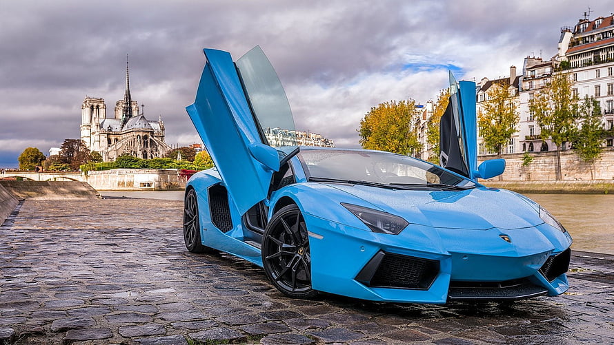 Blue Lamborghini Aventador with Open Doors Parked on Cobblestones Near Notre Dame Cathedral in Paris HD wallpaper