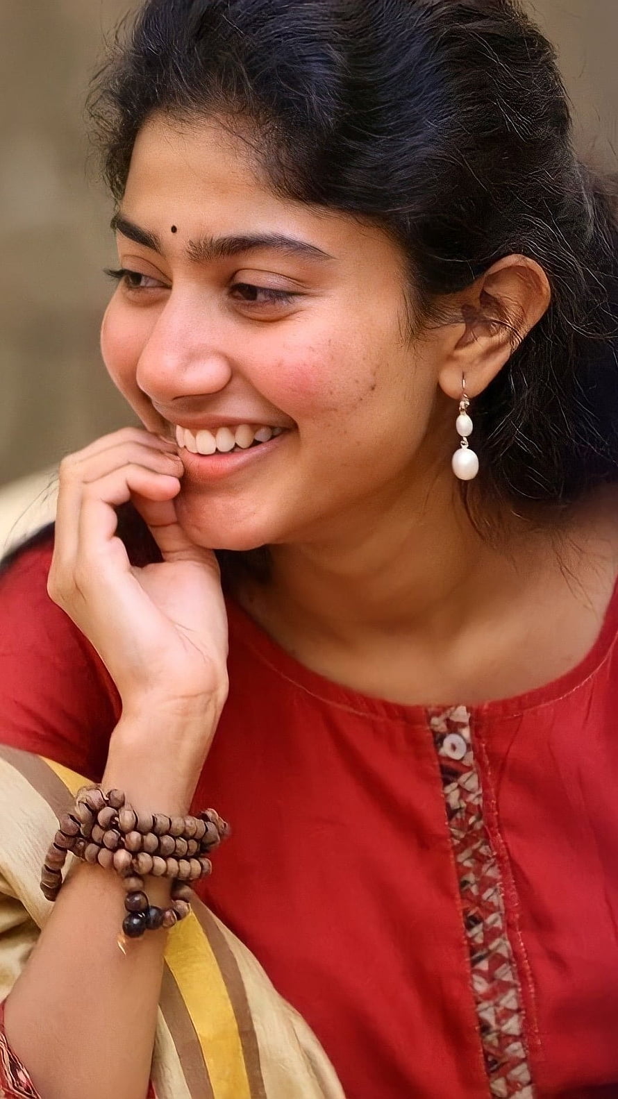 Portrait of a smiling woman wearing a red kurta and traditional wooden bead bracelets, South Heroine, Sai Pallavi, Tollywood Beautiful Actress HD phone wallpaper