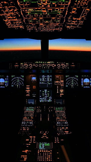 Commercial Airplane Cockpit at Night with Glowing Instrument Panels and Sunset Horizon View HD phone wallpaper