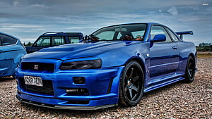 Blue Nissan Skyline GT-R R34 Widebody Coupe with Rear Spoiler on Gravel HD wallpaper