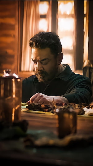 A bearded man in a dark green sweater sits at a rustic wooden table, intently examining a plate of food in a warmly lit cabin interior., Kamal Hassan, tamil movie, vikram HD phone wallpaper