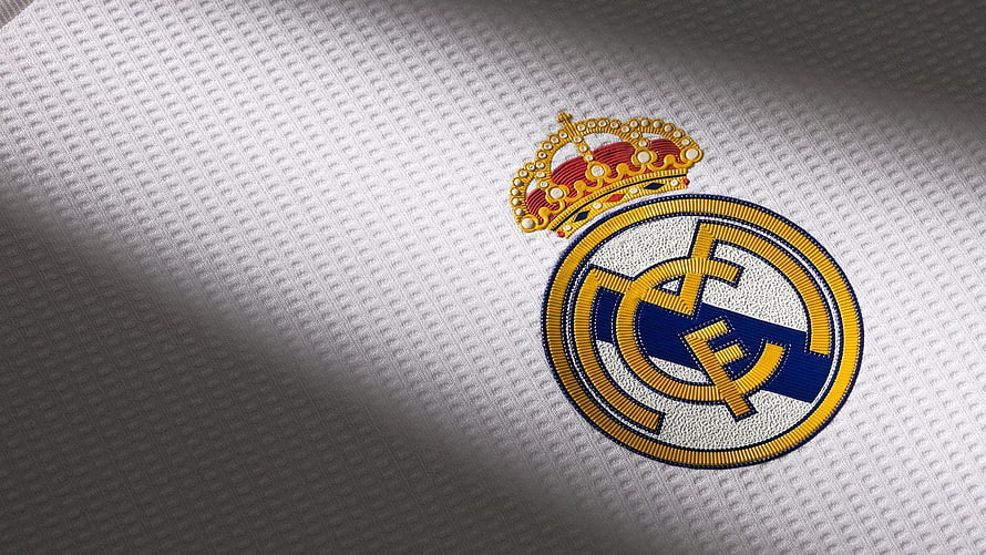 Real Madrid CF embroidered club crest on white textured football jersey fabric HD wallpaper