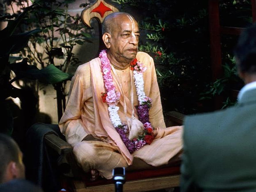 Srila Prabhupada Seated in Meditation Wearing Traditional Saffron Robes and Floral Garland HD wallpaper